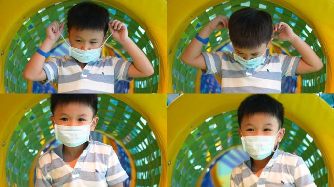 亚洲孩子戴着医用口罩在室内操场玩耍。保护概念