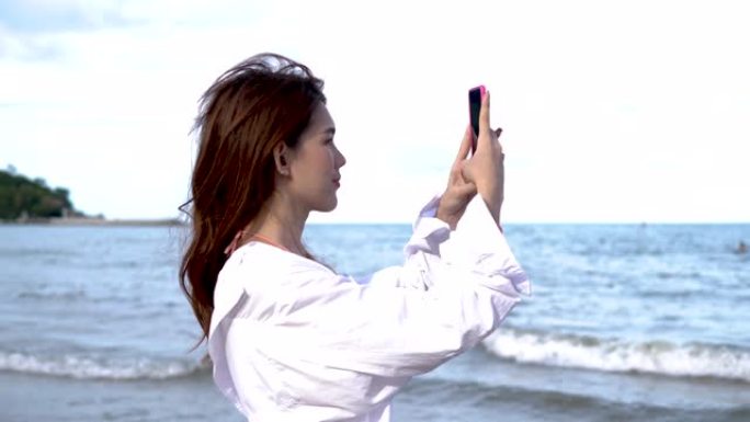 快乐的亚洲海滩女人在自拍，社交媒体上的海滩和风景。