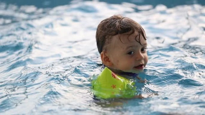 学步的男孩学习游泳，婴儿戴着手臂漂浮物