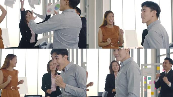 一群亚洲商业团队的人在现代办公室的工作场所跳舞和扔文件庆祝成功，这是一个有趣的企业，共同享受实现目标