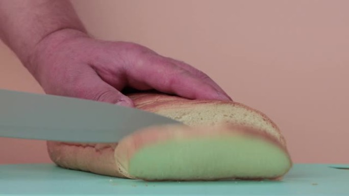 男性双手用小刀慢动作切开白面包。