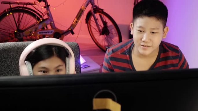 快乐的亚洲儿童在晚上在家玩网络游戏，带led灯背景，生活方式理念。