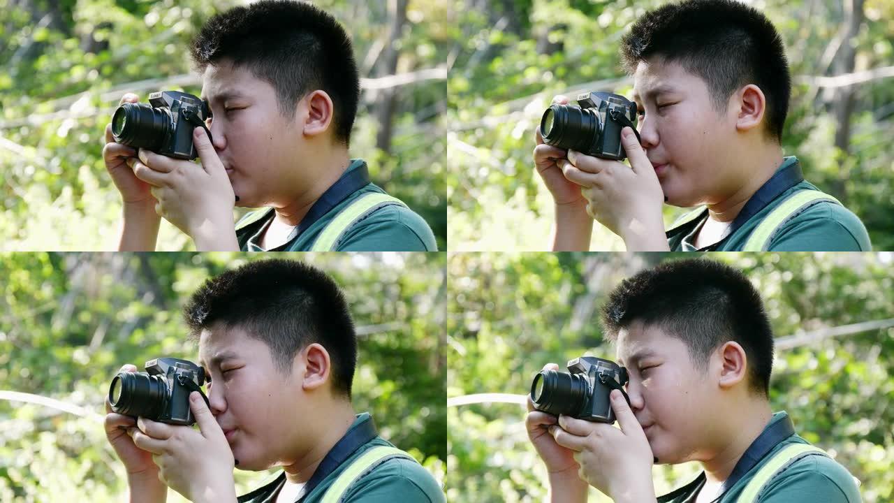 亚洲男孩学习使用相机如何拍摄自然背景，冒险概念。