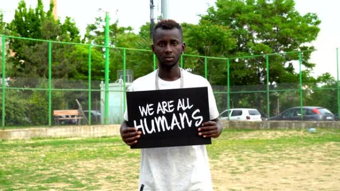 年轻的非洲抗议者手持纸板“我们都是人”