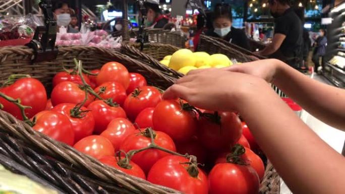 女人的手在市场上拿了几个西红柿
