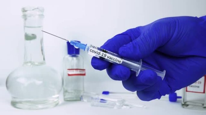 疫苗注射器与铭文冠状病毒疫苗接种，手持药物，演示补救病毒，特写。