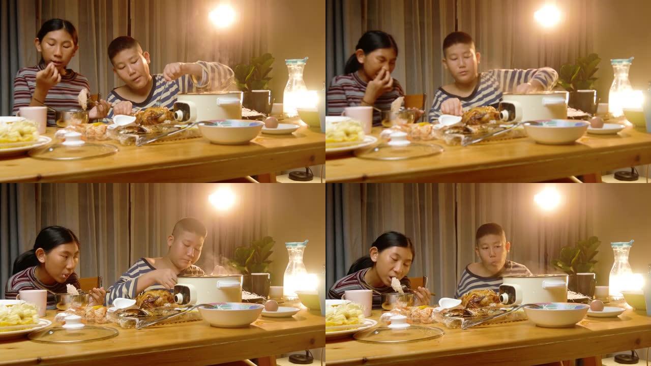 快乐的亚洲男孩和女孩在家一起享用sha锅或寿喜烧火锅和烤鸡作为晚餐，生活方式理念。
