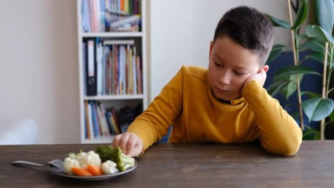 孩子对不得不吃蔬菜非常不满。他的盘子里有很多蔬菜。他讨厌蔬菜。