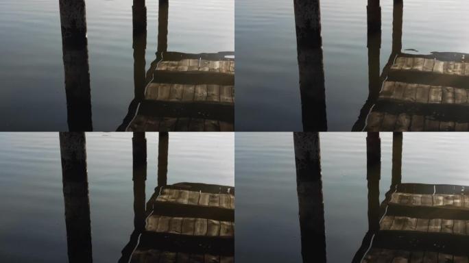 木制渔桥在河流的倒影中，河流，湖泊的平稳摇曳。河边的日落。