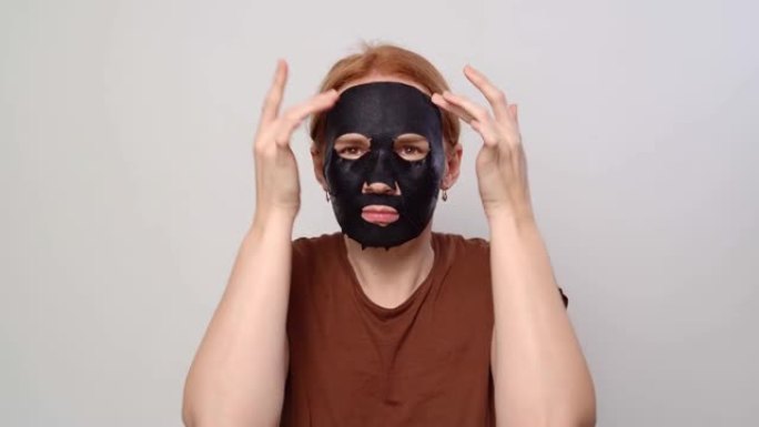 一个女人在脸上抹上黑色化妆品面膜。