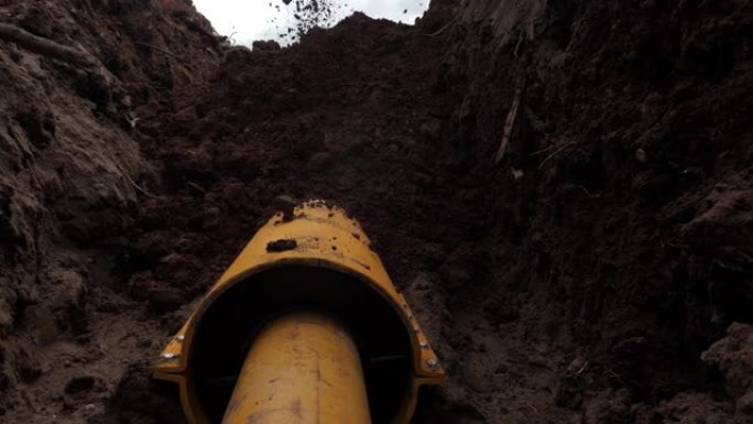 挖掘机将地面倒在用套管保护的管道上