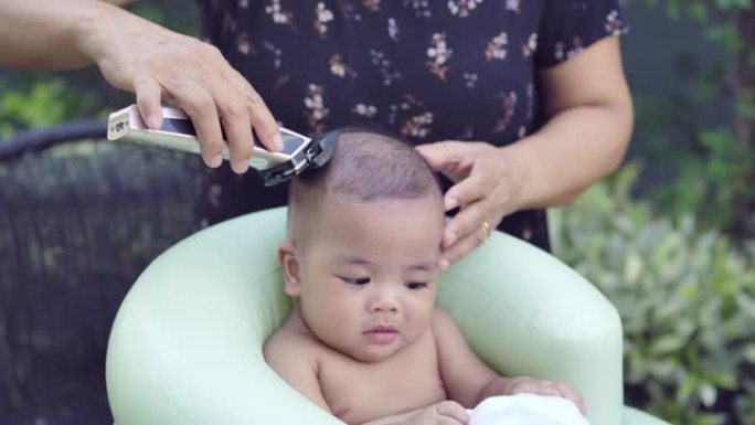 男婴第一次家庭DIY理发由祖母后院户外花园日场景剃光头发