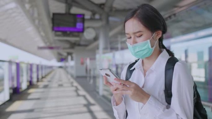 亚洲女商人戴着医用口罩使用智能手机，等待运输大众列车。面罩保护冠状病毒和pm2。概念社会距离