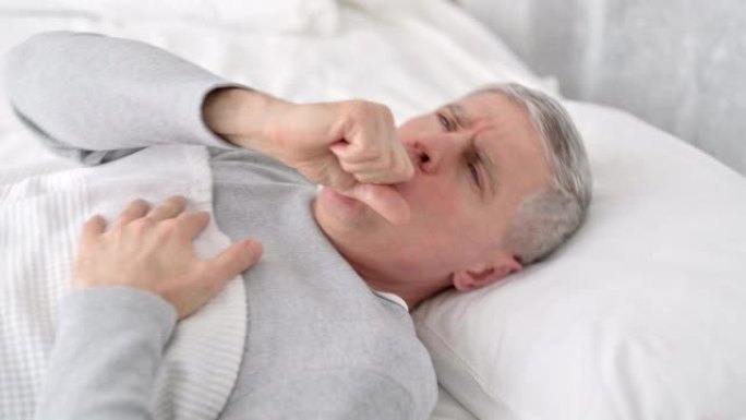 生病的资深老人睡在床上咳嗽