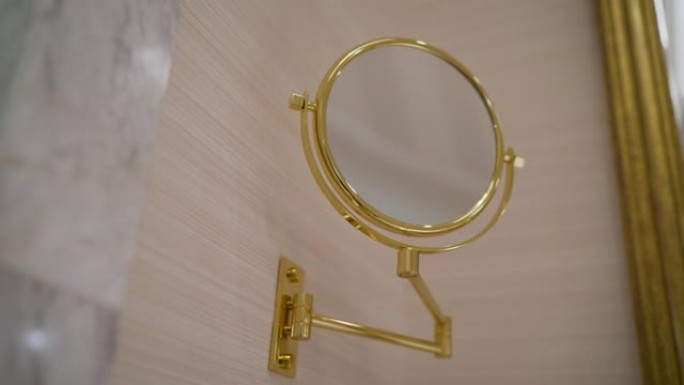 新浴室，图案壁纸，闪闪发光的地板，圆形镜子，装饰金色框架和黑色盆。浴室里的一面圆形金色镜子。