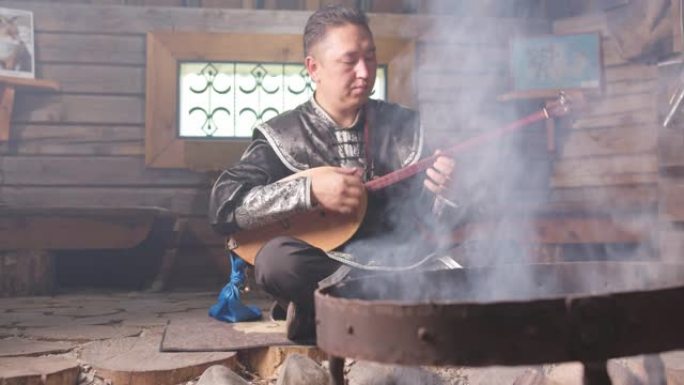 一位穿着东方服装的亚洲音乐家蜷缩在壁炉前。