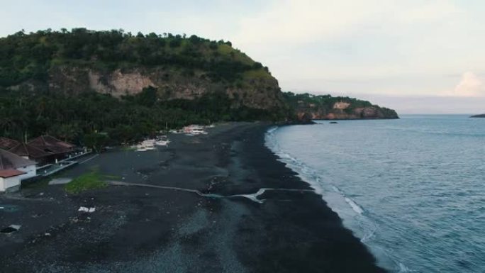 空中无人机无人机在背景中观察了一个emty黑沙滩和热带海岸线山丘