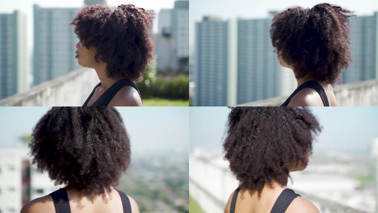 年轻的非洲裔美国妇女望着远处的天际线建筑在屋顶上。女性运动员在运动装中确定，有复制空间