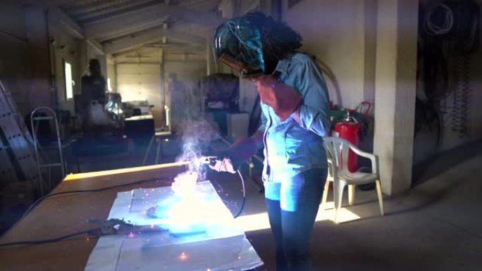 在工厂工作的年轻女焊工穿着防护安全装备