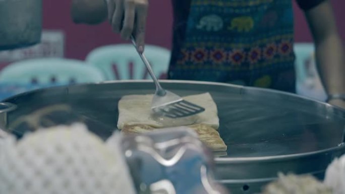 围裙中的男人在煎锅中烹饪带有金色外壳的食物