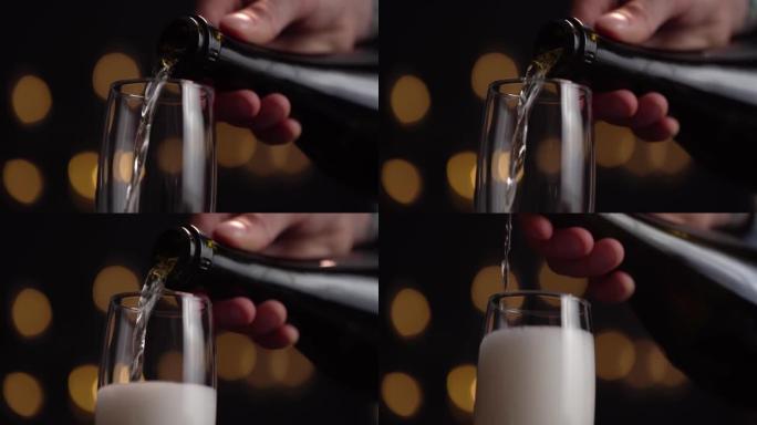 调酒师的特写镜头将香槟倒入黑色背景上的玻璃杯中，玻璃杯中有很多泡沫和气泡。概念假期，新年，圣诞节，生