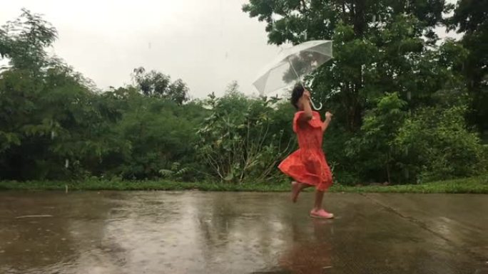儿童亚洲女孩带伞在雨中在街上奔跑