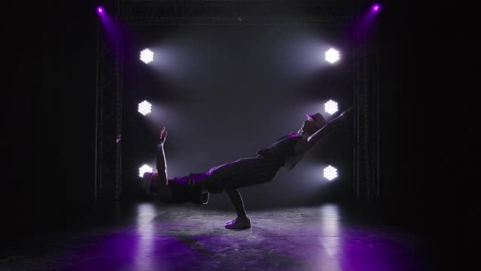 两名男性体操杂技演员摆出平衡姿势。强壮的运动男子在团队合作中表演复杂技巧的剪影。在黑色背景上的聚光灯