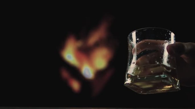 一杯威士忌，黑底有火，手里拿着酒精饮料，侍酒师拿着一杯威士忌。
