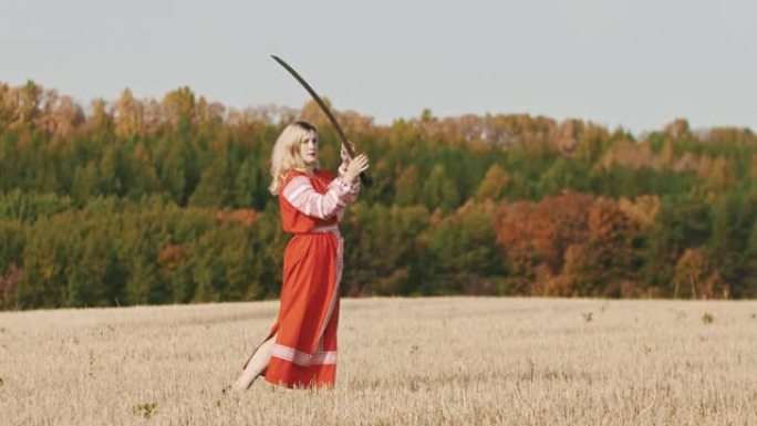 身穿红色民族服装的争强好斗的女子在训练场上挥舞着一把剑