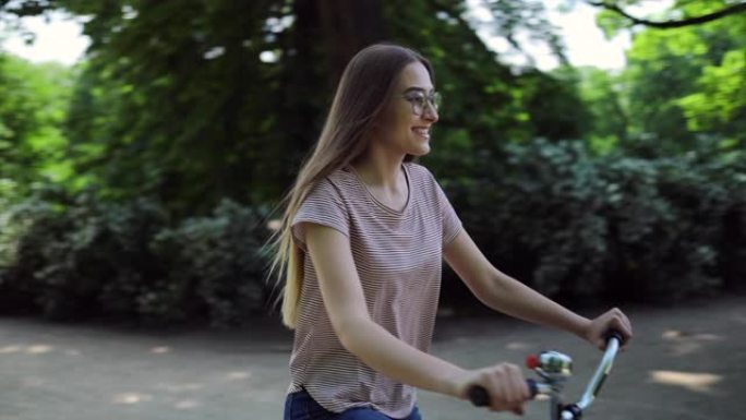 迷人的年轻女子骑自行车穿过公园