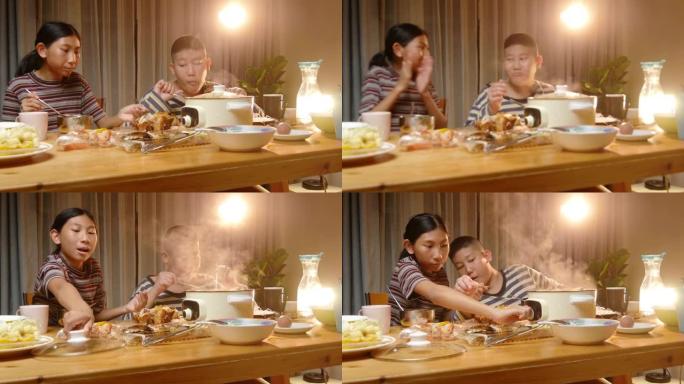 快乐的亚洲男孩和女孩在家一起享用sha锅或寿喜烧火锅和烤鸡作为晚餐，生活方式理念。