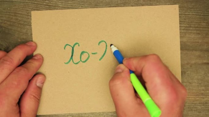 一只男性用蓝色毡尖笔在纸板xo-xo-xo上写字。