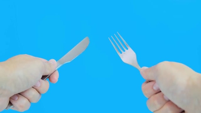 一个在蓝色背景下拿着叉子和刀的人，一个来自第一人的饥饿男人的概念