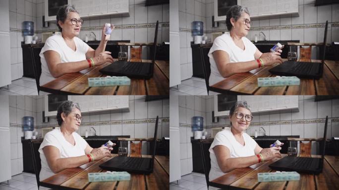 在医生视频咨询中，在笔记本电脑前的一名高级妇女展示了一个药瓶，然后看着相机
