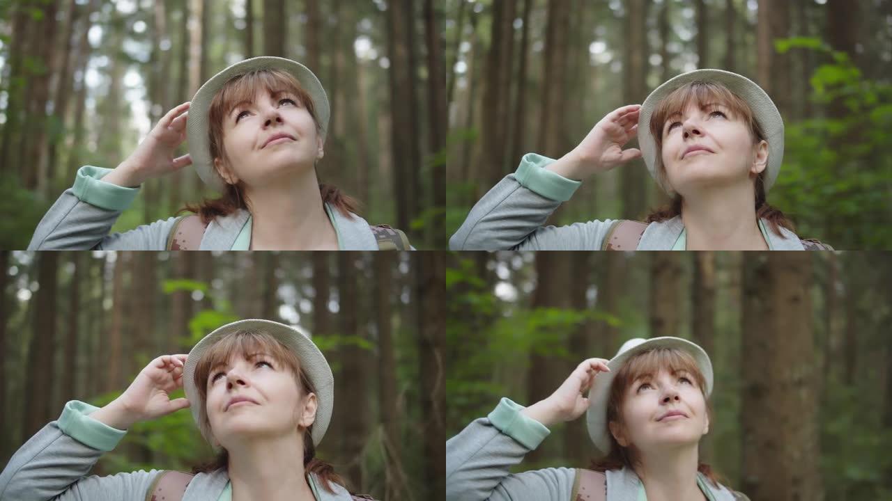 森林里戴帽子的女人环顾四周，在地球上旅行