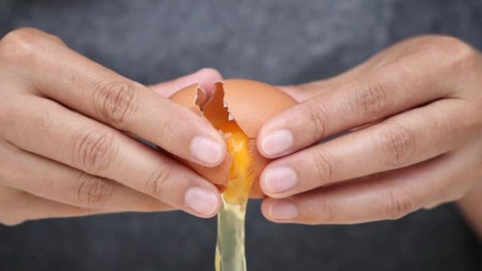 关闭破裂的新鲜鸡蛋，慢动作女人的手打碎鸡蛋。