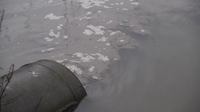 污浊废水流出混凝土排水管进入城市池塘