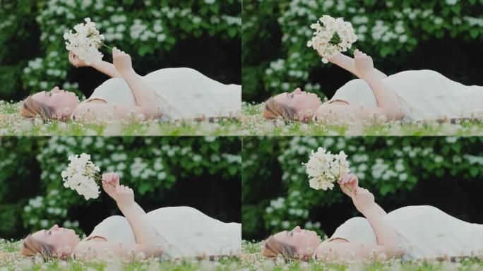 迷人的孕妇躺在草坪上捧着一朵花