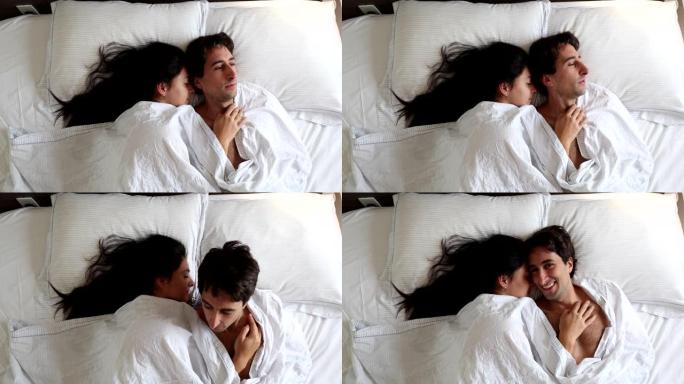 夫妇早上躺在毯子下的床上