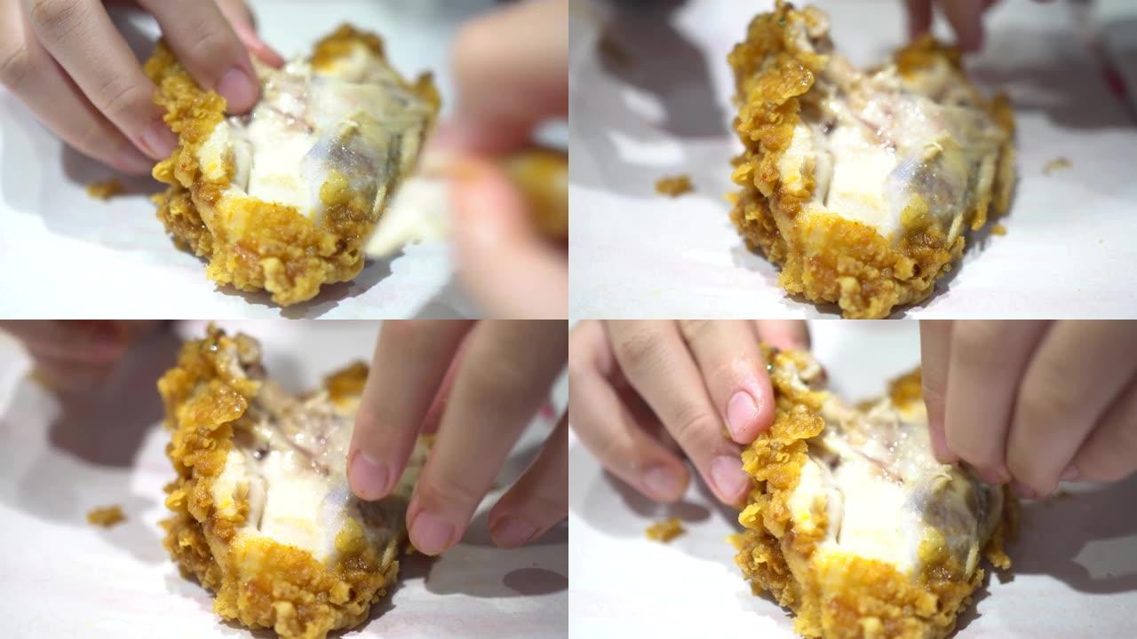 一个小孩在快餐店吃炸鸡。用手把鸡撕开。