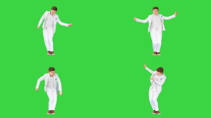 穿着白色西装的小男孩在绿色屏幕上跳舞，色键