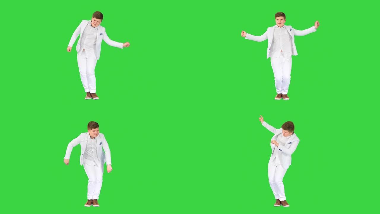 穿着白色西装的小男孩在绿色屏幕上跳舞，色键
