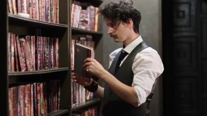 穿着时髦的男人在一个古老的黑暗图书馆里翻阅老式书籍。特写视图