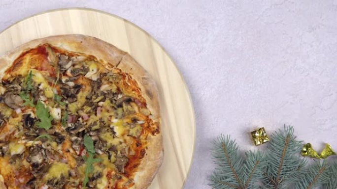 平放的比萨饼旋转360度旋转在木制的salver，圣诞装饰品周围。