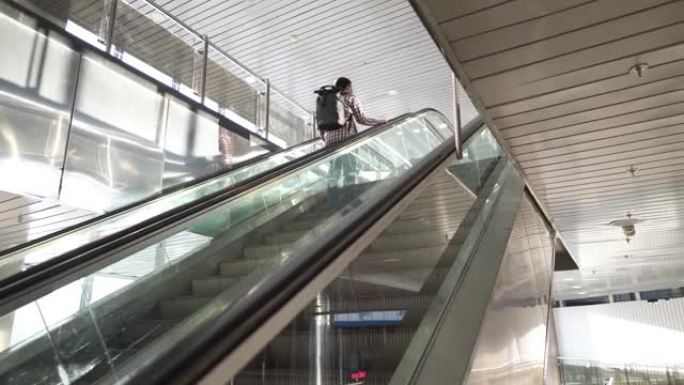 空荡荡的火车站大楼，在完全锁定检疫期间，自动扶梯上的唯一乘客戴着防护口罩。取消航班和运输崩溃covi