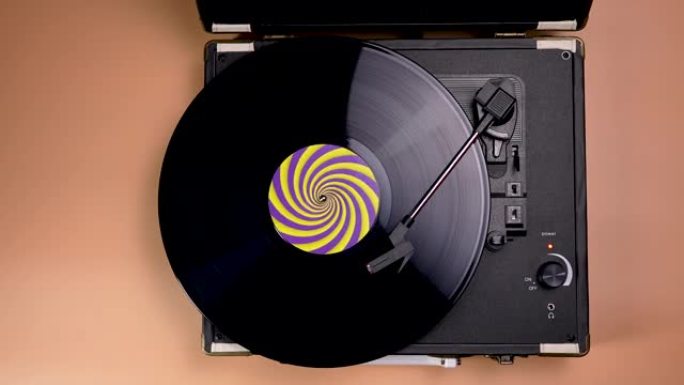 俯视图老式好看的转盘播放音乐，棕色背景上有乙烯基。带有黄色紫色标签的黑色黑胶唱片以慢动作在复古音乐播