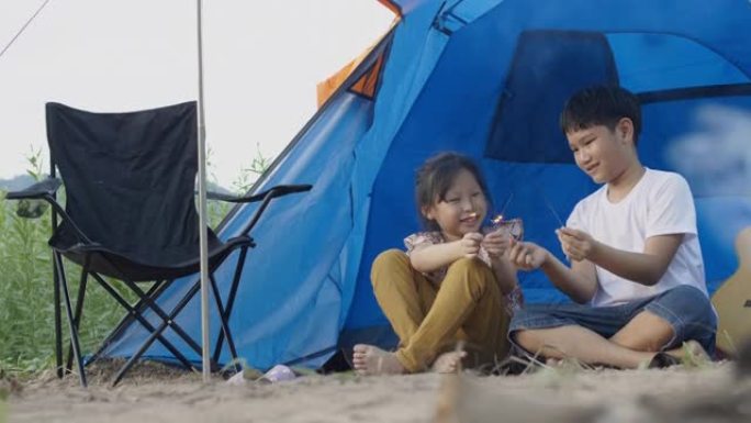 亚洲男孩和女孩在度假时与家人露营时玩烟花