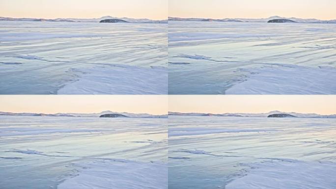 雪在冰面上飞舞。雪花在贝加尔湖的冰上飞舞。冰非常美丽，有不同寻常的独特裂缝。背景视图山景。雪闪闪发光