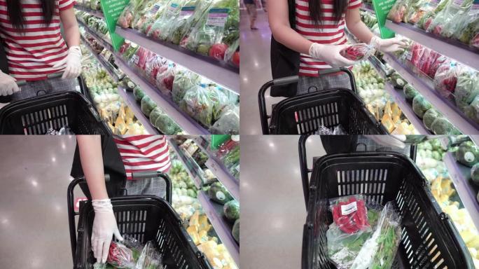 女人的手戴着防护手套，在杂货店选择蔬菜。