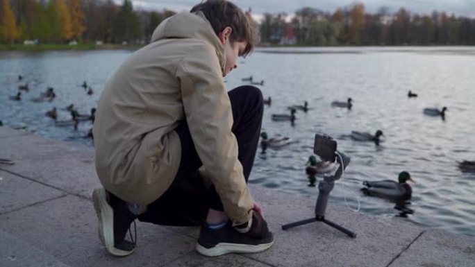 公园里用手机摄像头稳定器录制视频博客的视频记录器男孩